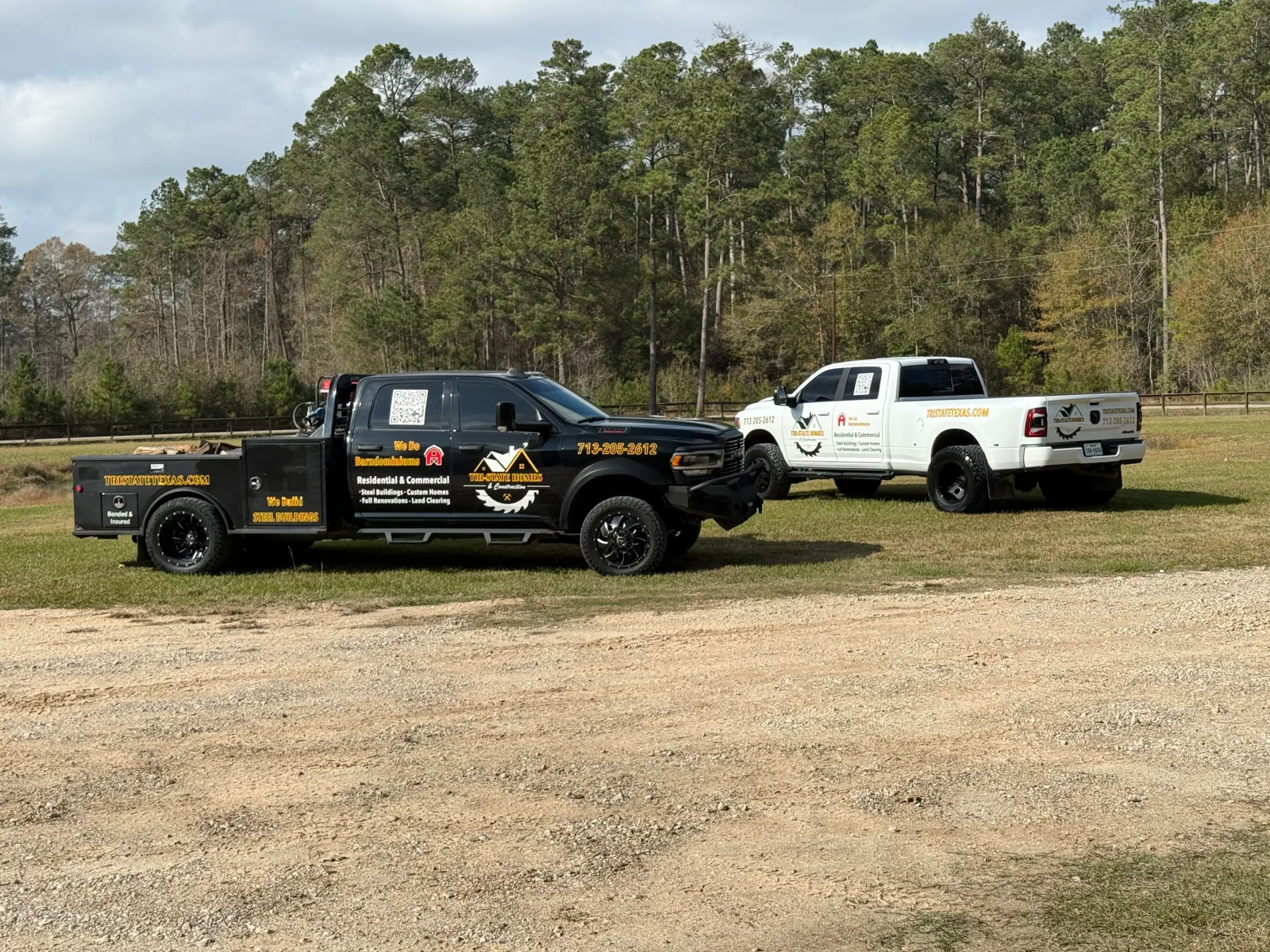 Black flatbed and white dually work trucks with vinyl lettering for steel buildings, custom homes, and renovations