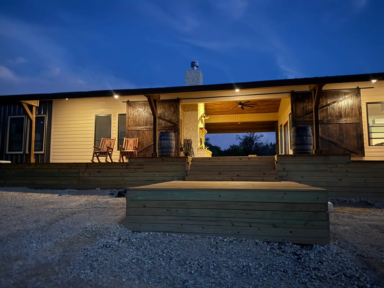 Covered back porch with stone fireplace, wood plank ceiling, barn-style sliding doors, and multi-level wood deck