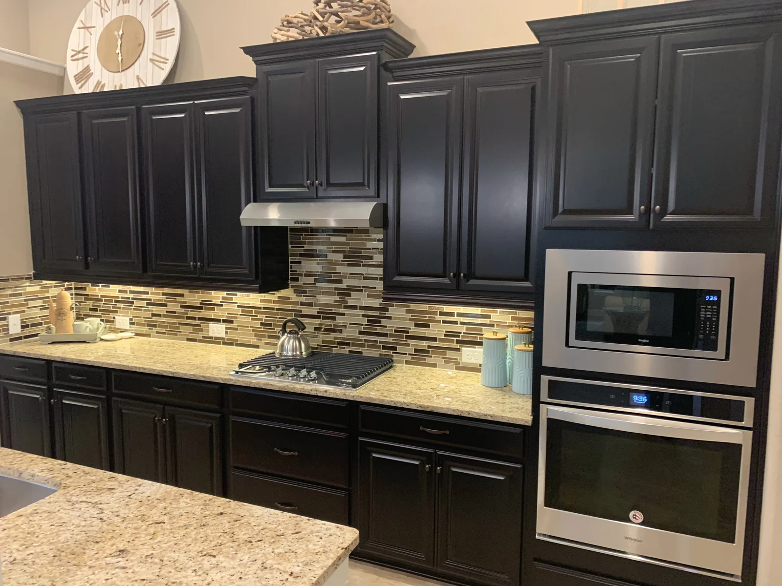 Dark espresso raised-panel kitchen cabinets with granite countertops and linear glass tile backsplash